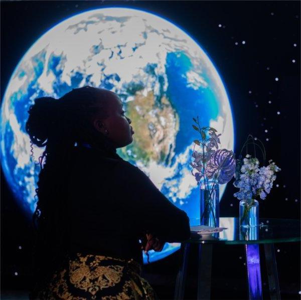 A visitor to GVSU's "The Blue 点经验," event is silhouetted against an image of the Earth.